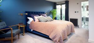 bedroom in loft conversion with feature blue wall and pink bedspread