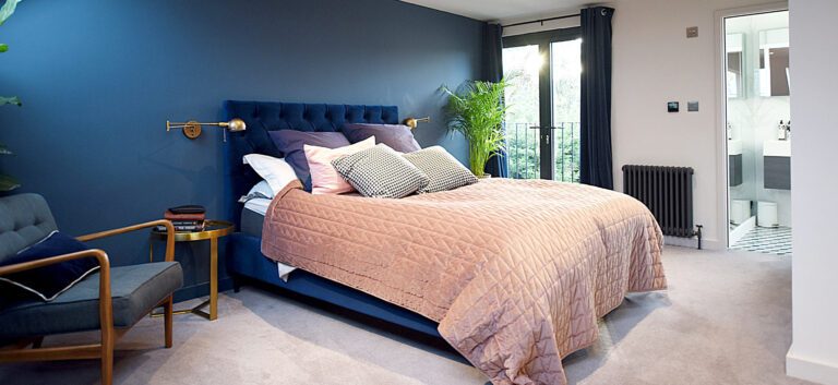 bedroom in loft conversion with feature blue wall and pink bedspread