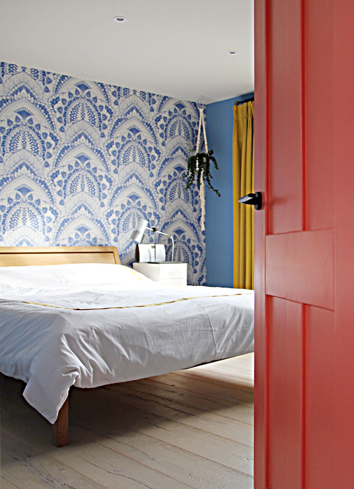 red door opening onto loft bedroom in blue and yellow